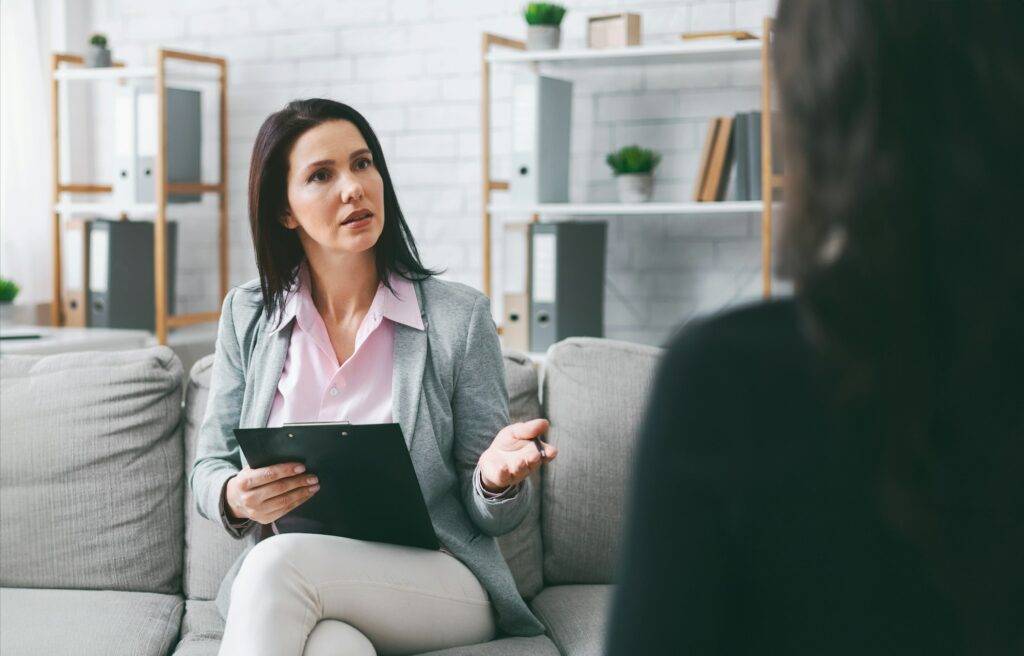 Woman Therapist Talking To Patient In Office Setting During Therapy